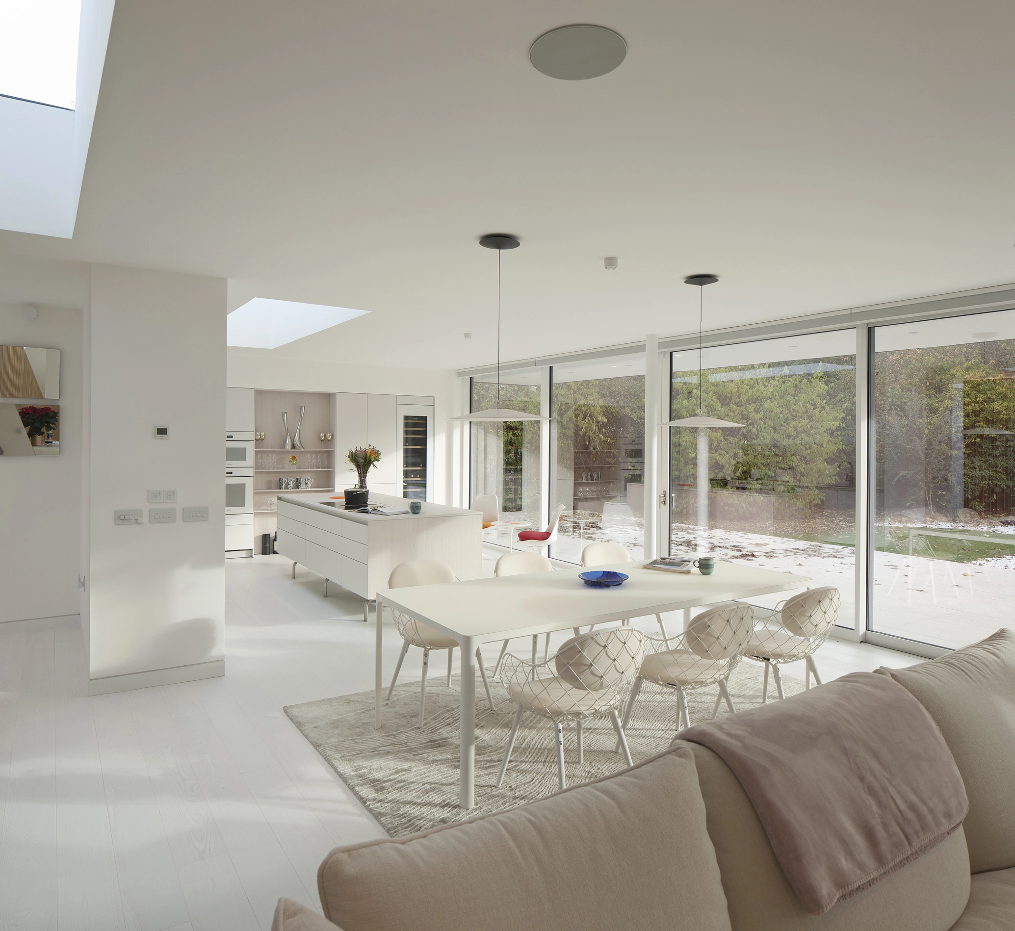 The open-plan-living, dining and kitchen of a recently renovated home designed by NVDC architects in Glasgow, with white walls and hardwood timber floors, strategically placed rooflights to provide lots of natural light and a bespoke kitchen design.